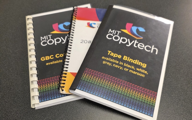 Three bound booklets show examples of plastic comb binding, spiral plastic coil, and adhesive tape binding.